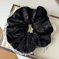 Detail van zwarte fluwelen haarelastiek met witte kantrand in een houten sieradendoos - Zwart