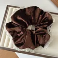 Detailweergave van de grote donkerbruine fluwelen scrunchie met witte kanten rand - Donkere Koffie