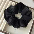 Detail of denim scrunchie with orange contrast stitching in a jewelry display box - Black