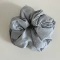 Vue détaillée du chouchou gris clair oversize avec texture de tissu et petite étiquette interne - Bleu clair