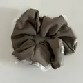 Detailed texture of brown fabric scrunchie with white lace trim and pearls - Dark Khaki