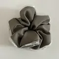 Close-up detail of mesh lace edges and white pearl beads on a brown fabric hair scrunchie - Khaki