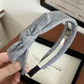 Detail of grey ribbed knit headband featuring a stylish side bow and comfort end tips - Gray