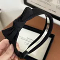Detailed close-up of a vintage black knitted bow headband with ribbed fabric texture - Black