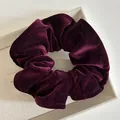 Close-up of a burgundy velvet scrunchie with detailed stitching on a beige jewelry box - Burgundy