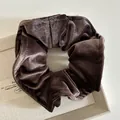 Detailed view of large dark brown velvet scrunchie with soft sheen on textured background - Brown