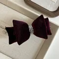 Dettaglio del fermaglio a fiocco in velluto bordeaux con decorazione di perle finte - Borgogna