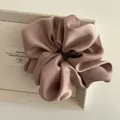 Close-up of a large dusty rose satin scrunchie with elegant pleated fabric texture - Pink