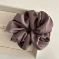 Close-up of silk satin scrunchie in mauve color with elegant folds and soft texture - Purple