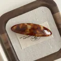 Macro detail of tortoiseshell acetate hair clip with golden France Handmade stamp - Light Brown Marble