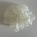 Detailed close-up of ivory pearlescent organza scrunchie with soft ruffled texture - Off White