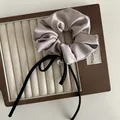 Dettaglio scrunchie in raso talpa con fiocco nero e un elegante ciondolo di perle - Rosa Loto