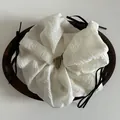 Detail of a large cream-colored scrunchie with delicate black satin bows on a wood tray - White