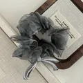 Detailed texture of gray organza hair scrunchie with satin bow on wooden tray - Gray