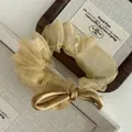 Detailed close-up of champagne gold organza scrunchie with silk bow on a wooden jewelry tray - Champagne Gold