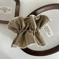 Detalle de un coletero de rayas caqui con textura plisada sobre una bandeja de madera - Caqui