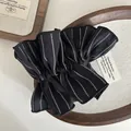 Detalle de coletero de rayas negras con diseño plisado sobre una bandeja de madera - Negro
