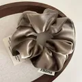 Brown velvet scrunchie hair tie with brand tag on a rustic wooden tray holder - Khaki