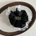 Detailed macro view of black satin scrunchie with layered white pleated mesh lace trim - Black