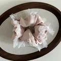 Detail of light pink satin scrunchie with white double-layer mesh ruffles on linen tray - Pink