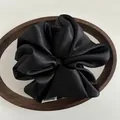 Macro view of a large black satin scrunchie with smooth silk-like texture and brand tag - Black