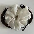 Detail of white chiffon oversized scrunchie with black ribbon bow on wooden tray - Off-white
