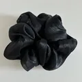 Λεπτομέρεια μαύρου σατέν scrunchie με πλισέ υφή και μεταξένια γυαλιστερή εμφάνιση - Μαύρο