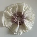 Detail of oversized layered scrunchie with beige ruffles and pink center with silver label - Pink