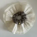 Detail of multi-layered lace scrunchie with grey fabric and golden metal label - Grey Brown