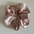 Dettaglio di uno scrunchie in raso rosa chiaro con texture perlata e cuciture sottili - Rosa