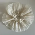 Close-up of cream-colored ruffled hair scrunchie with layered design and gold emblem - Off White