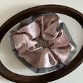 Detail von rosa Satin-Haargummi mit grauer Netzspitze in einer ovalen Holzschale - Rosa