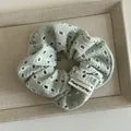 Detail of mint green eyelet fabric scrunchie with a Happy Every Day woven label - Mint