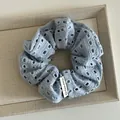 Detail of light blue hollow knit scrunchie with Happy every day woven label - Blue