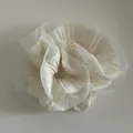 Macro view of ivory ruffled organza hair scrunchie with layered fabric texture - Off-white