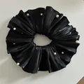 Detalle macro de coletero de satén negro plisado con elegantes perlas blancas - Negro