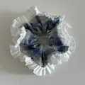 Detail shot of blue plaid scrunchie featuring elegant double-layered white ruffled edges - Blue