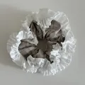Close-up of brown checkered scrunchie with white pleated ruffle edges for hair styling - Khaki