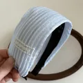 Close-up of blue striped wide headband with delicate lace detail and embroidery - Blue
