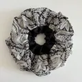 Macro detail of oversized paisley satin scrunchie showing floral pattern and texture - Black