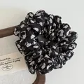 Primer plano detallado del coletero vintage negro con flores y capas de tela plisada - Negro