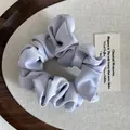 Detailopname van de lichtpaarse satijnen haarelastiek op een houten decoratief dienblad - Blauw