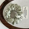Detailopname van mintgroene satijnen scrunchie met elegante plooien en gladde textuur - Groen