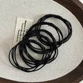 Macro shot of five black high-elasticity braided hair ties on a rustic wooden tray - Woven Multi-strand Style (Style A)