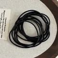Close-up of high-elasticity black hair ties with reinforced joints on a rustic tray - Spiral Texture Style (Style D)