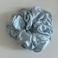 Macro detail of sky blue ruffled silk scrunchie with elegant pleated fabric texture - Blue
