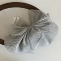 Close-up of translucent polka dot mesh bow hair clip with textured fabric details - White