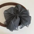 Detail of oversized black polka dot mesh bow hair claw clip on vintage wooden frame - Black
