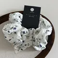 Weißes Haargummi mit blauen Blumenmustern und koreanischem Etikett auf einem Tablett - Weiß mit blauen Blumen