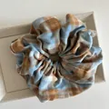 Macro view of blue gingham cotton scrunchie with detailed stitching on fabric - Blue and Coffee